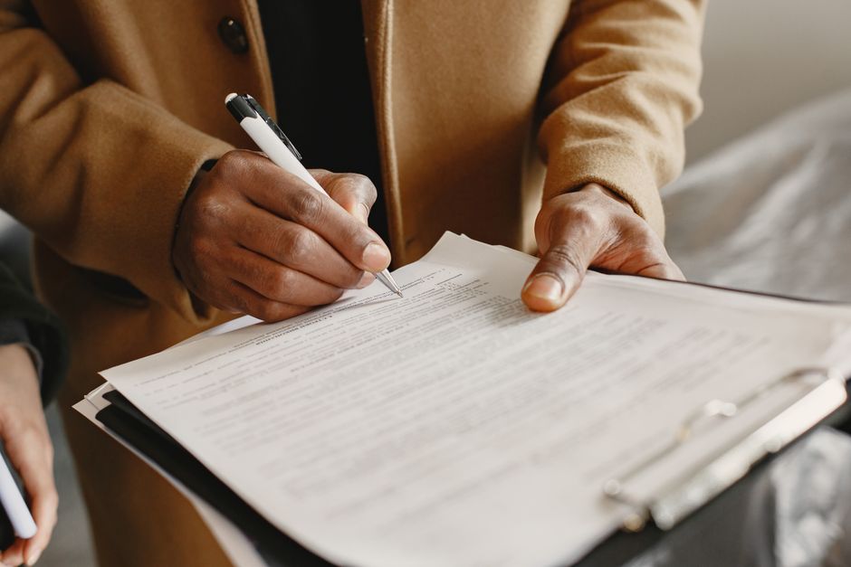 A close-up view of a development agreement document laid out on a wooden surface, partially covered by a yellow folder. Next to the document is a black and silver pen, and a notepad with blank lines.